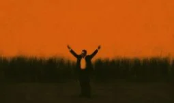 a small man with his arms in the air against an orange background 